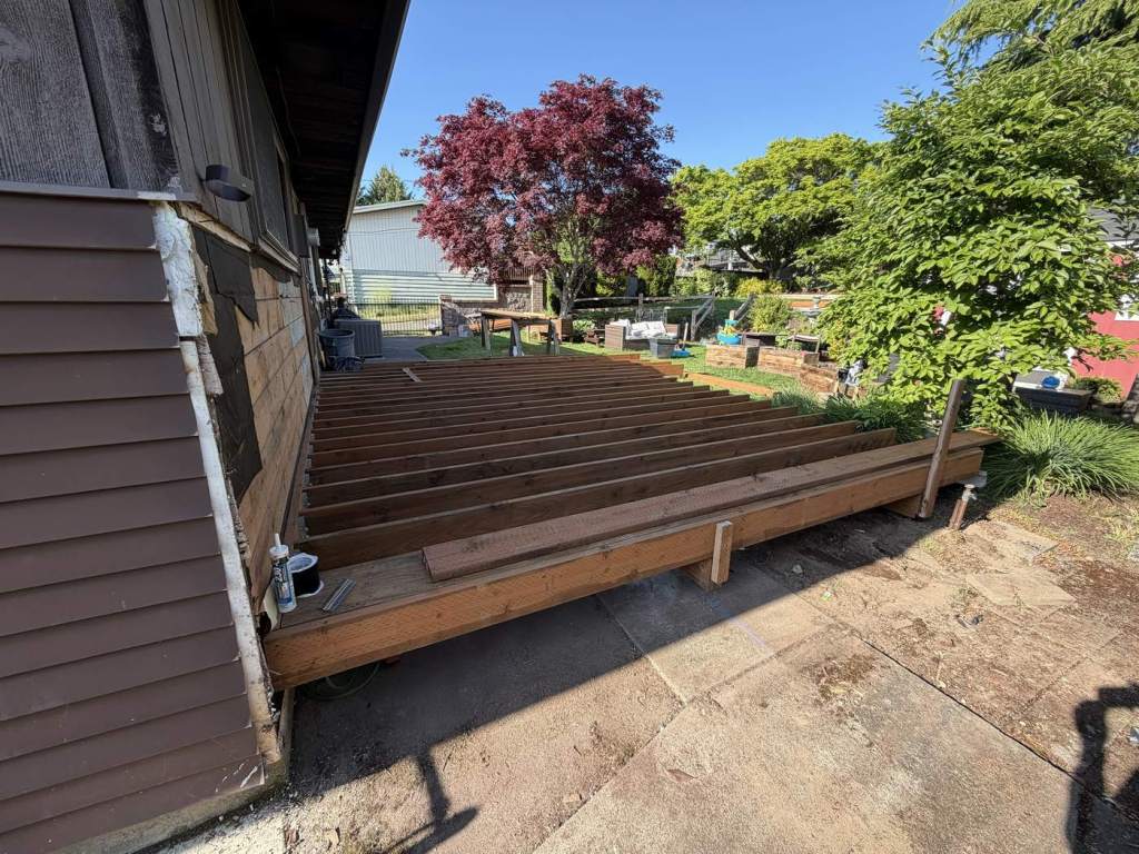 New pressure-treated framing with the ledger fastened and flashed against the house wall.