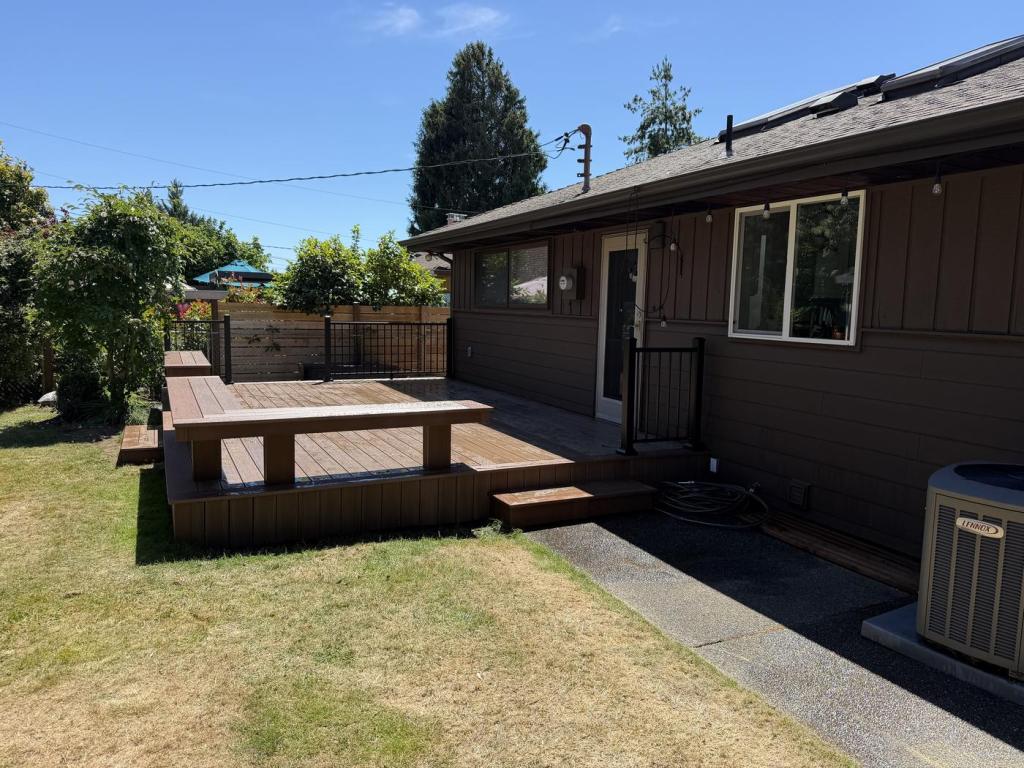 Wide view of the rear of the house with the new siding complete and the deck in place.