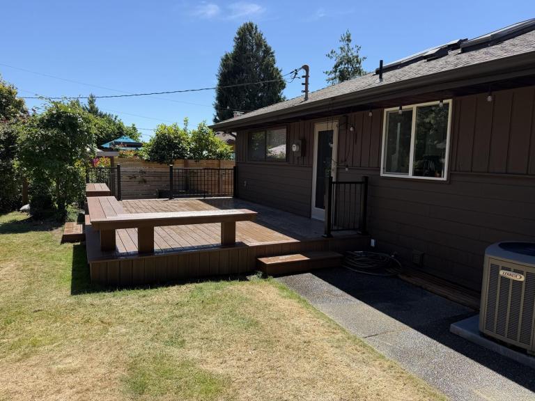 Wide view of the rear of the house with the new siding complete and the finished deck in place.