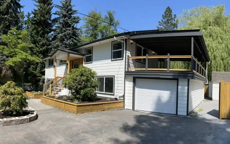 Renovated split-level home with white lap siding, a covered deck over the garage and new cedar planter beds