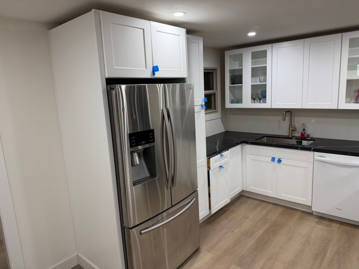 The perimeter counter and cabinets in the finished Burien kitchen, white cabinetry with stainless appliances