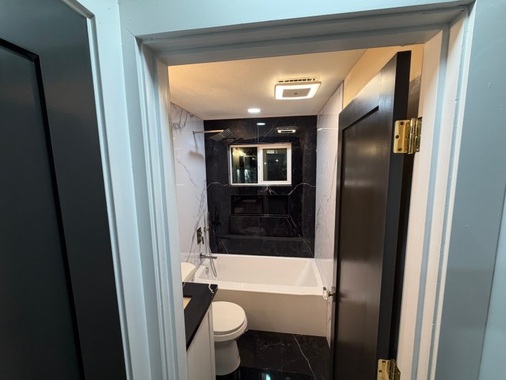 View into the finished Burien bathroom from the doorway, black-and-white vinyl paneling throughout
