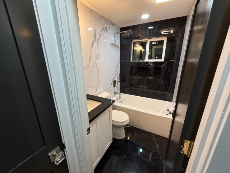 The finished Burien bathroom toward the black-countertop, white-cabinet vanity and toilet