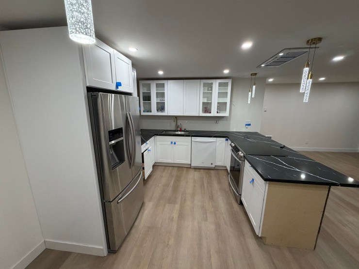 Another angle of the finished Burien kitchen, stainless fridge and black waterfall island