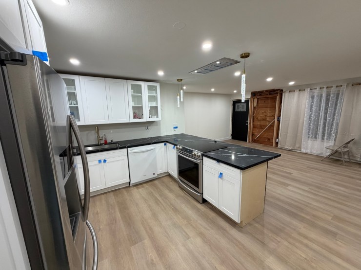 Finished Burien kitchen along the back wall, white cabinets, stainless range and fridge