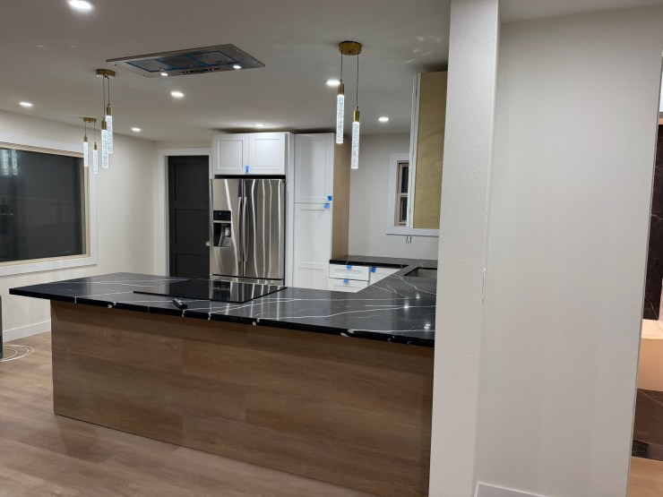 The black waterfall island and open sightline through to the living room in the finished Burien kitchen