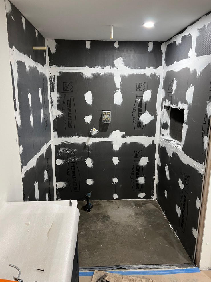 Waterproofing membrane taped and sealed at the seams in the primary bathroom shower