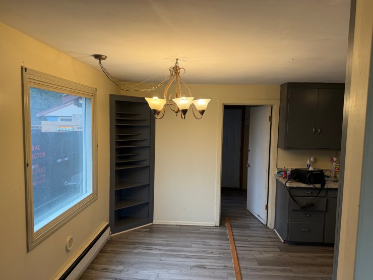 Dining nook before the Burien remodel, with a dated chandelier and built-in shelving