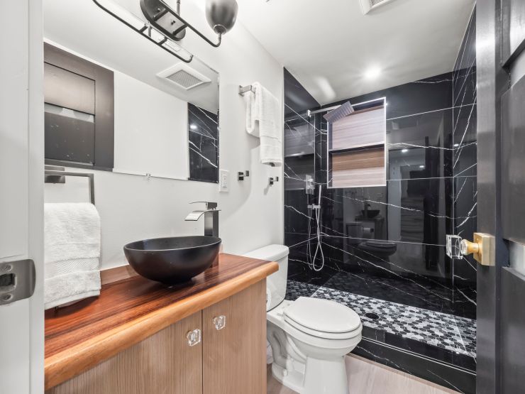 The finished Tacoma bathroom with the wood-top vanity, black vessel sink and tiled shower in the same frame