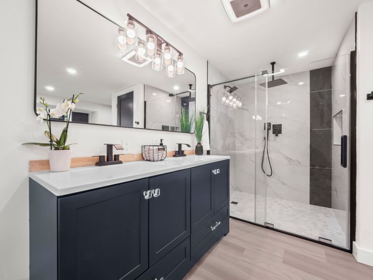 The navy vanity and glass-enclosed shower in the primary bathroom